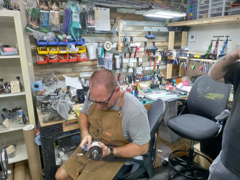 Staff member working on a fishing reel at the counter